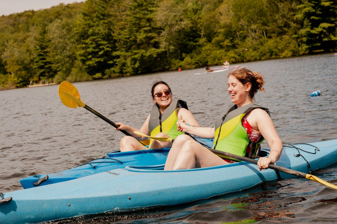 Women kayaking together during a lakeside retreat at Camp Social