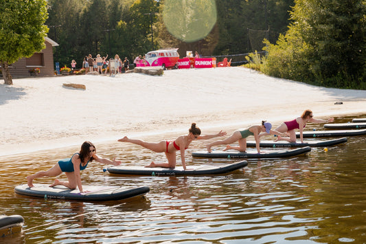 Women enjoying paddleboard yoga on the lake at Camp Social