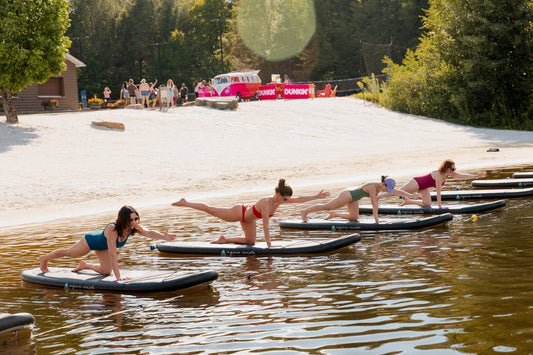 Women enjoying paddleboard yoga on the lake at Camp Social