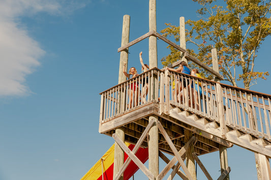 Campers at the top of a wooden waterslide tower at Camp Social