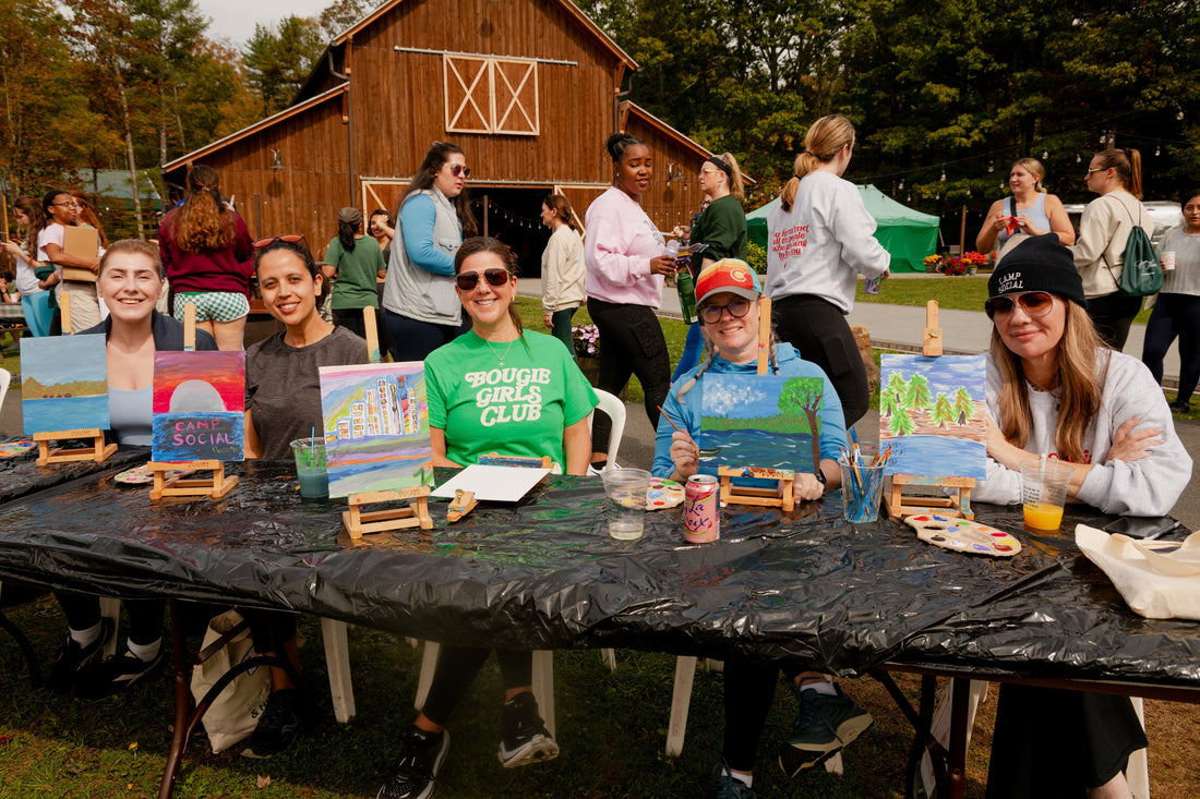 Women painting outdoors during creative activities at Camp Social
