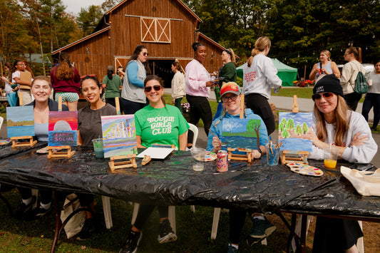Women painting outdoors during creative activities at Camp Social