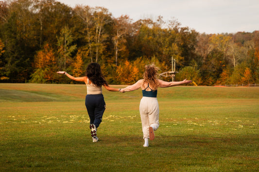 Two people running across a grassy field by Camp Social