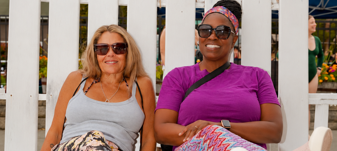 Two women relaxing on a giant white chair at adult summer camp by Camp Social